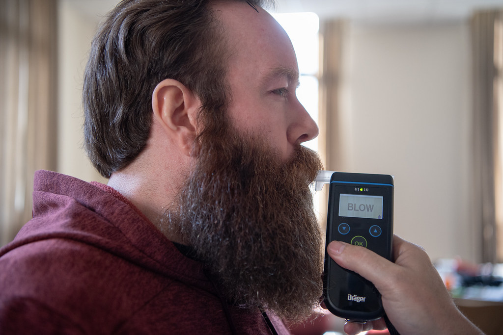 A driver provides a breath sample into a handheld breath-testing device at the roadside.